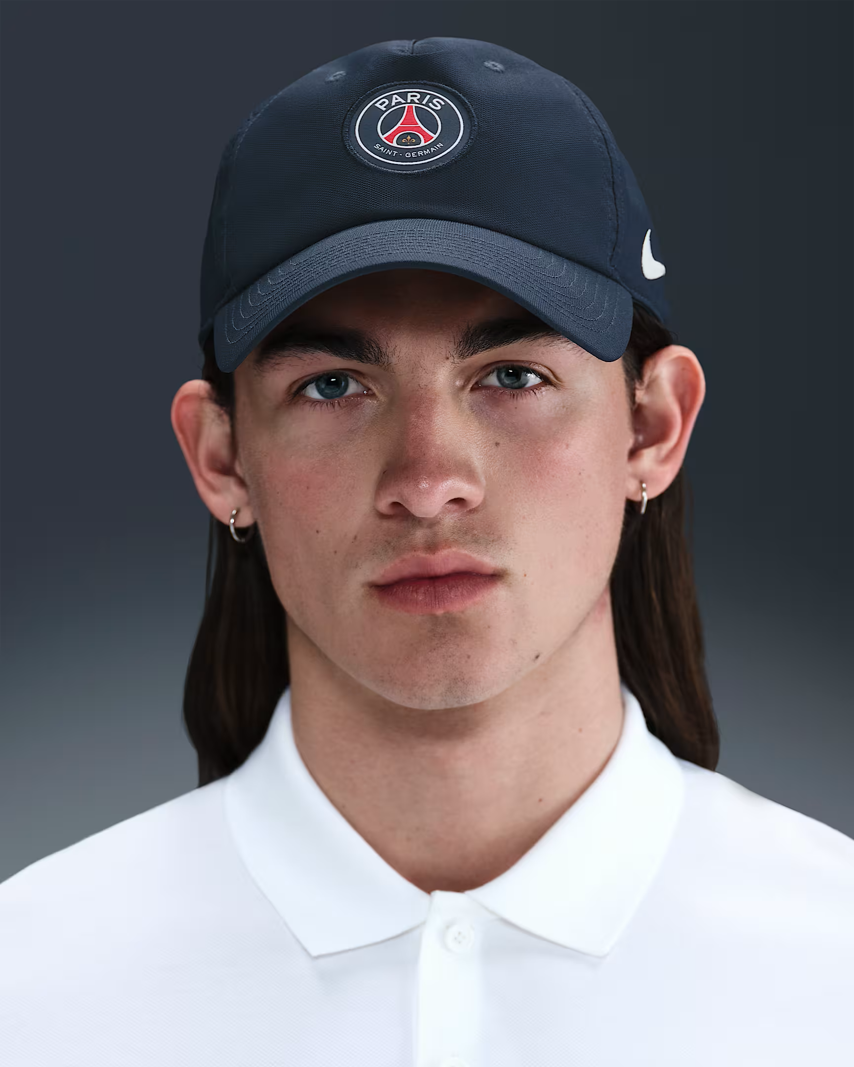 Person wearing a dark blue cap with a logo on a gray background